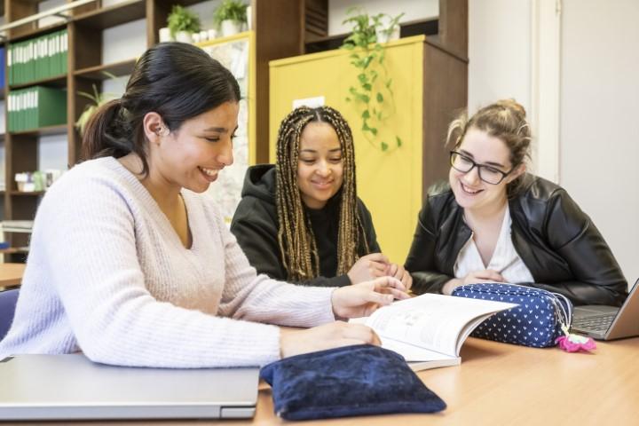 Drie studenten werken samen tijdens een groepswerk in Verpleegschool Antwerpen.